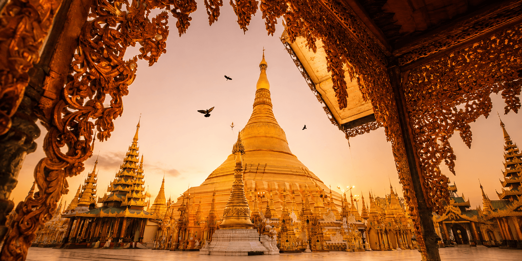 Golden Burmese pagoda framed by ornate temple carvings
